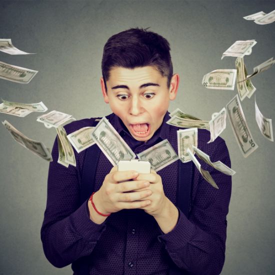 A man stands with mouth agape as dollar bills fly out of his hand.